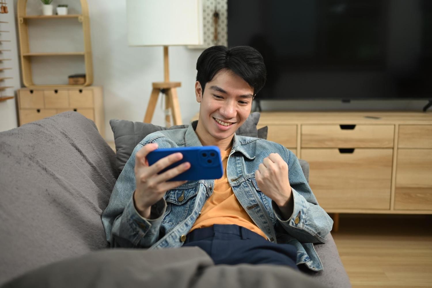 Man celebrating while playing game on smartphone at home